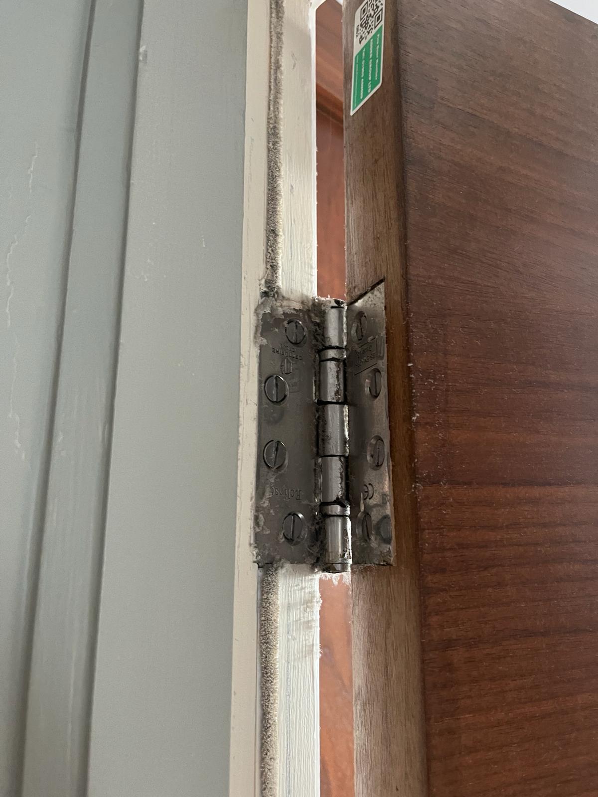 Fire Door Inspection - Common breach of fire door safety regulations - Intumescent strip/smoke seal has been painted over, and replacement hinge is required. 