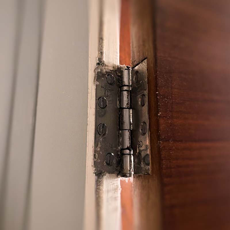 sqr_img_07 Fire Door Inspection - Common breach of fire door safety regulations - Intumescent strip/smoke seal has been painted over, and replacement hinge is required.